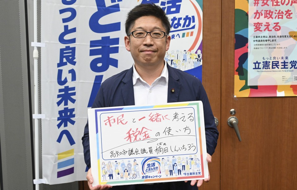 高知県高知市 楠目慎一郎市議がメッセージボードをもつ写真